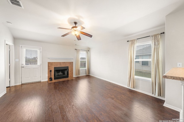 unfurnished living room featuring baseboards, visible vents, a ceiling fan, a tile fireplace, and wood finished floors