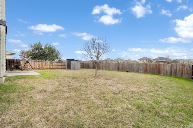 view of yard featuring a storage unit, a patio area, a fenced backyard, and an outdoor structure