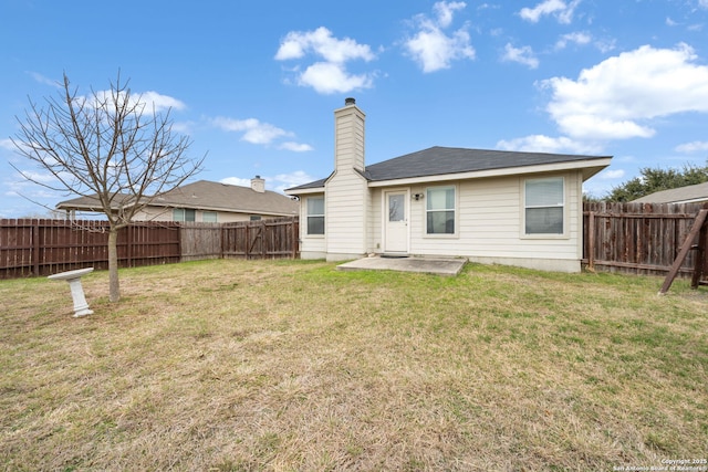 rear view of house featuring a patio area, a fenced backyard, a yard, and a chimney