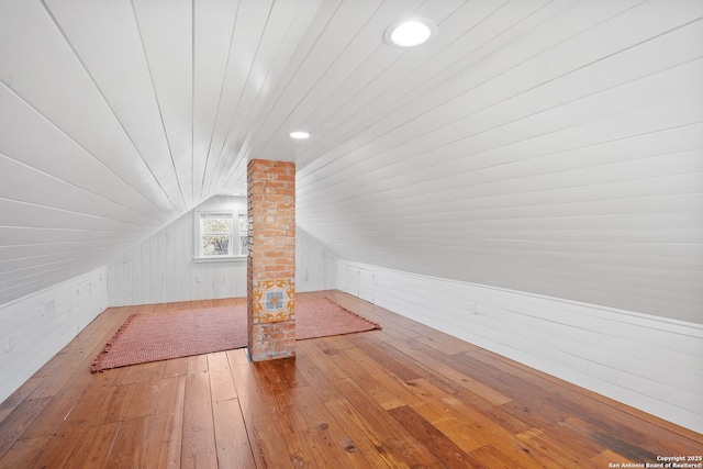 additional living space with lofted ceiling, wood ceiling, hardwood / wood-style floors, ornate columns, and wood walls