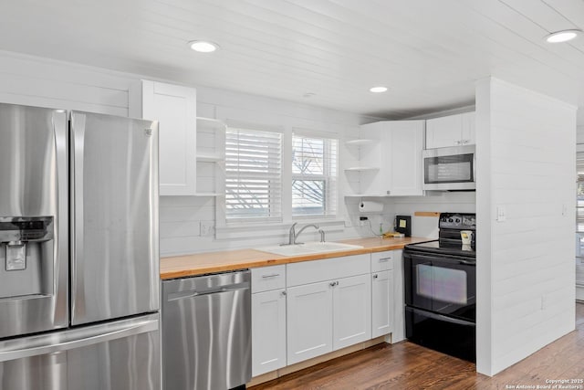 kitchen with a sink, white cabinets, wooden counters, appliances with stainless steel finishes, and open shelves