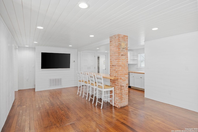 kitchen with wooden ceiling, hardwood / wood-style flooring, wood counters, visible vents, and white cabinets