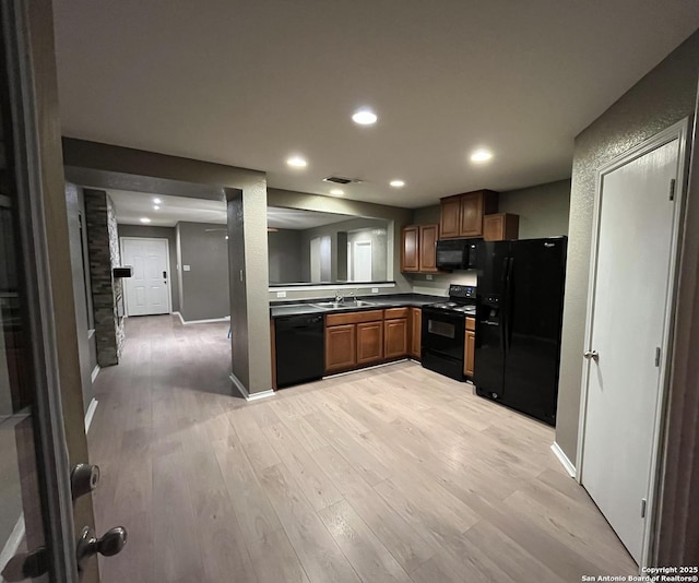 kitchen featuring dark countertops, visible vents, a sink, light wood-type flooring, and black appliances