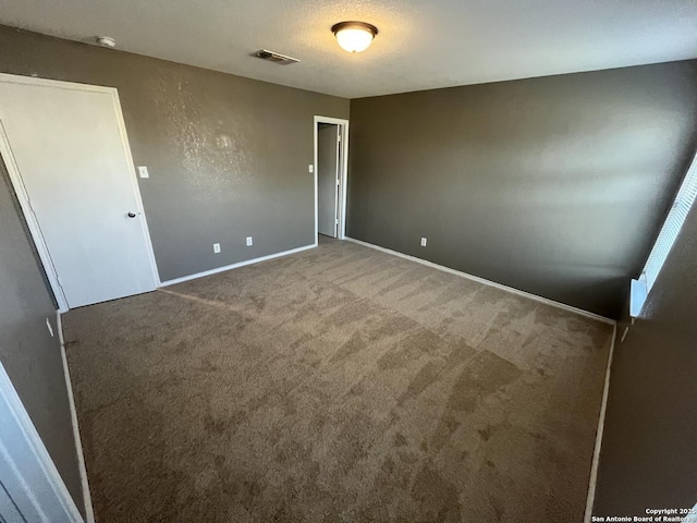 unfurnished bedroom featuring baseboards, a textured ceiling, visible vents, and carpet flooring