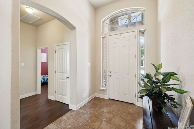 foyer with a healthy amount of sunlight, visible vents, a high ceiling, and arched walkways