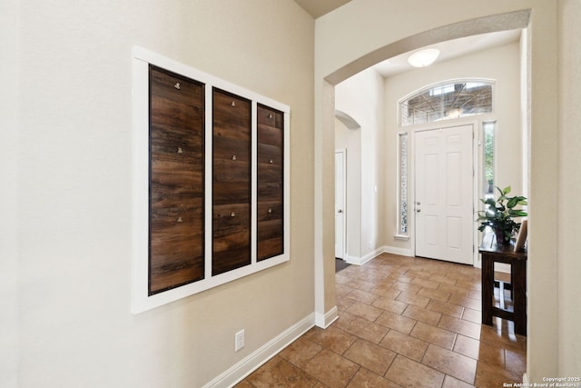 entryway featuring baseboards and arched walkways