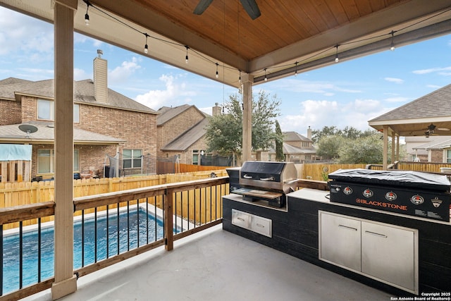 view of patio with grilling area, area for grilling, a ceiling fan, a fenced backyard, and a swimming pool