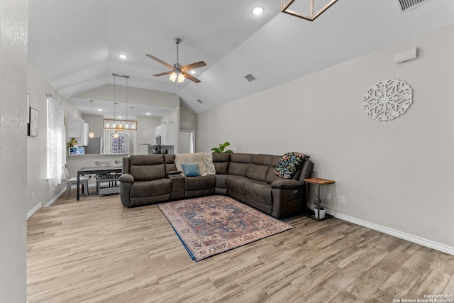 living room with ceiling fan with notable chandelier, vaulted ceiling, baseboards, and wood finished floors