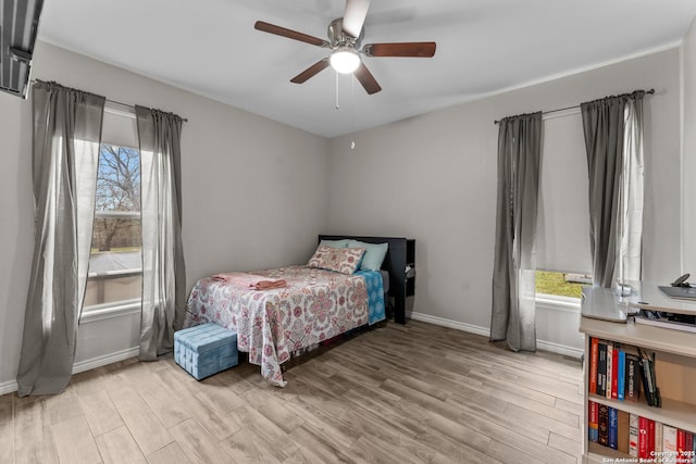 bedroom with light wood-style floors, multiple windows, and baseboards