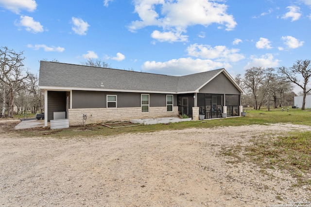 view of front of home with a sunroom, a shingled roof, stone siding, and stucco siding