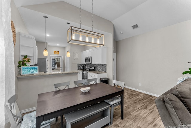 dining area featuring lofted ceiling, visible vents, light wood-style flooring, and baseboards