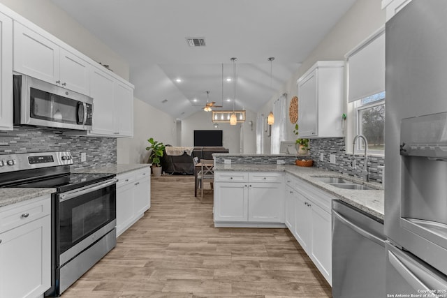 kitchen with visible vents, lofted ceiling, open floor plan, stainless steel appliances, and a sink