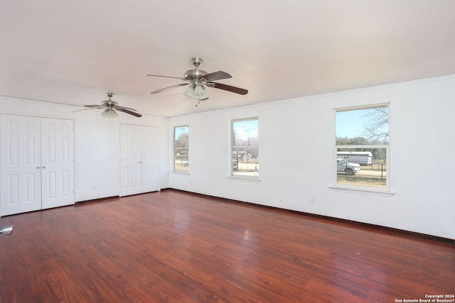 620 County Road 6846, Lytle, TX 78052 - unfurnished bedroom featuring dark wood-style floors, two closets, a ceiling fan, and baseboards