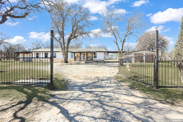 620 County Road 6846, Lytle, TX 78052 - view of front of house with a fenced front yard, gravel driveway, and a gate
