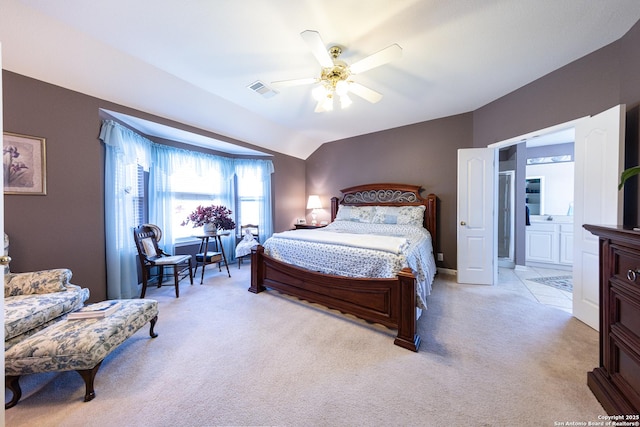 bedroom featuring light carpet, visible vents, a ceiling fan, lofted ceiling, and ensuite bath