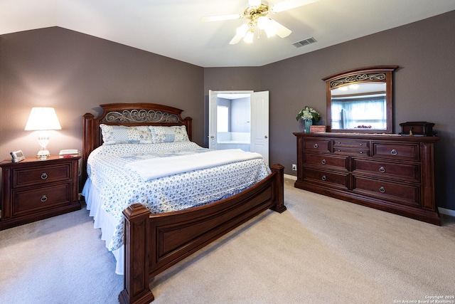 bedroom with ceiling fan, light carpet, visible vents, vaulted ceiling, and ensuite bath