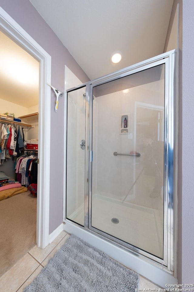 full bathroom with a stall shower, tile patterned flooring, and a spacious closet