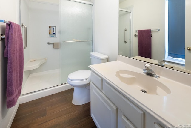 bathroom featuring vanity, a stall shower, wood finished floors, and toilet