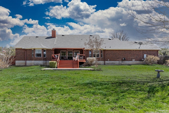 rear view of house with a wooden deck, fence, a lawn, and brick siding