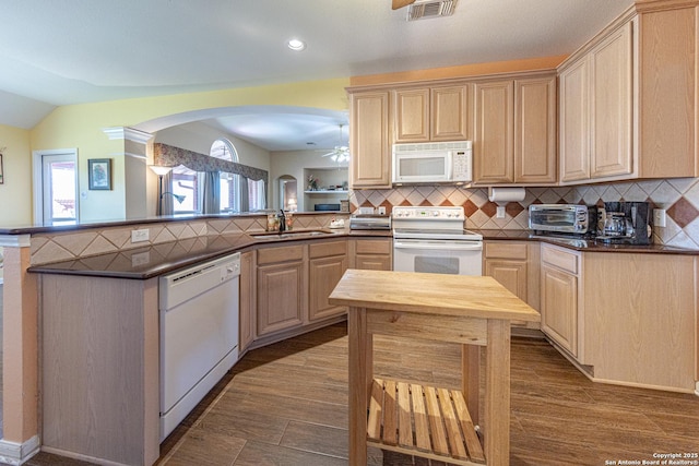 kitchen featuring tasteful backsplash, visible vents, a sink, white appliances, and a peninsula