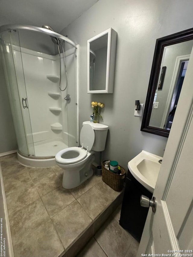 bathroom featuring toilet, a stall shower, a sink, and tile patterned floors