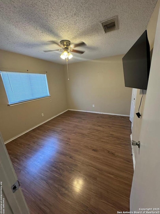 empty room featuring visible vents, baseboards, and wood finished floors