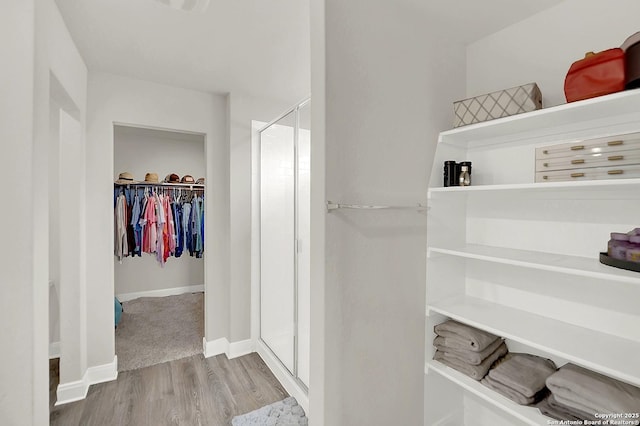 walk in closet with wood finished floors