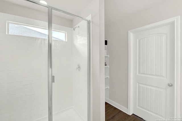 bathroom featuring a shower stall, baseboards, and wood finished floors