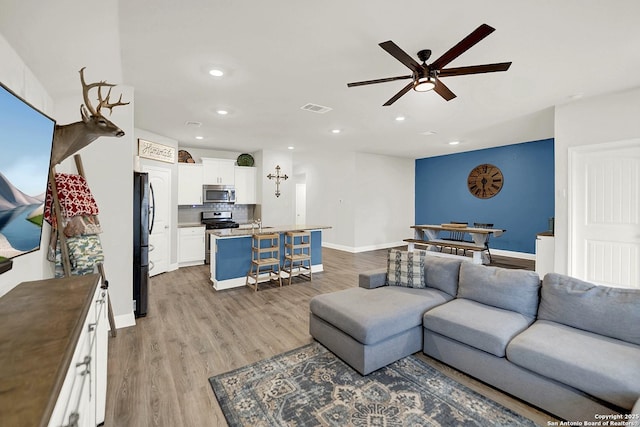 living area featuring visible vents, baseboards, a ceiling fan, light wood-style flooring, and recessed lighting