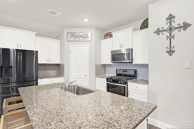 kitchen with tasteful backsplash, a center island with sink, visible vents, stainless steel appliances, and a sink