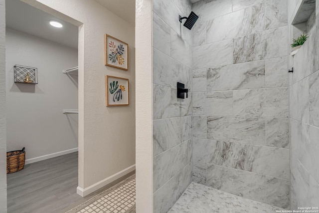 bathroom featuring tiled shower, baseboards, and wood finished floors