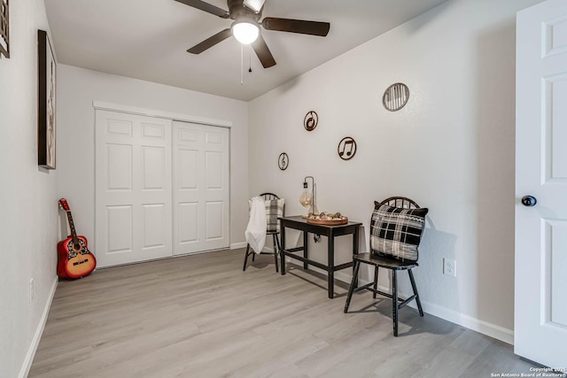 living area featuring ceiling fan, baseboards, and wood finished floors