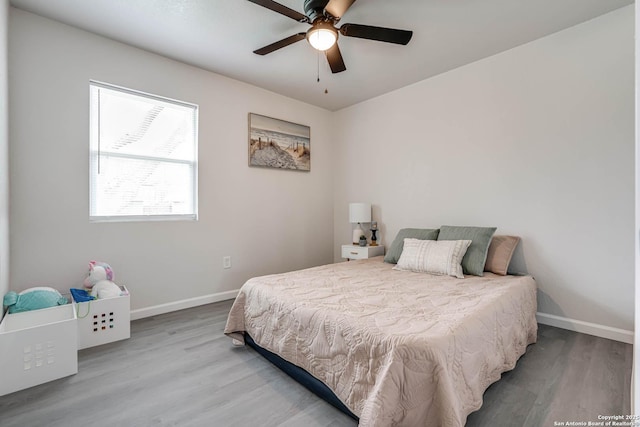 bedroom with a ceiling fan, baseboards, and wood finished floors