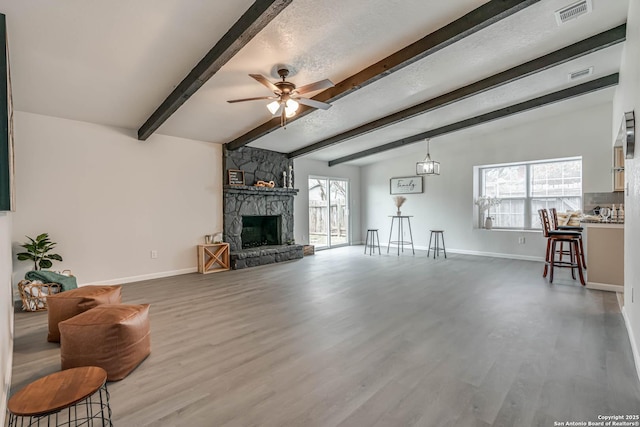 living room with a ceiling fan, visible vents, a fireplace, and wood finished floors