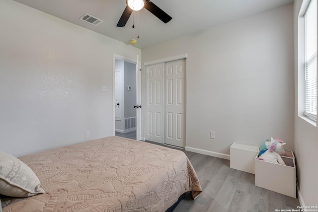 bedroom with baseboards, a closet, visible vents, and wood finished floors