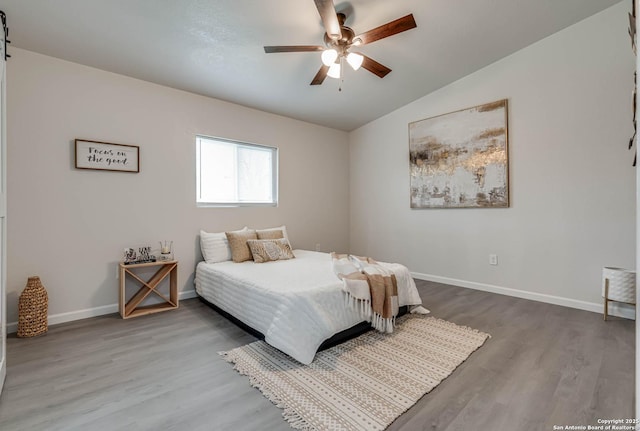 bedroom with ceiling fan, vaulted ceiling, baseboards, and wood finished floors