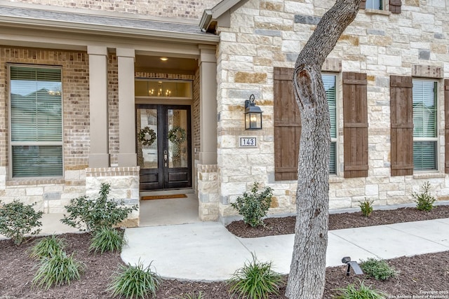 entrance to property featuring stone siding, brick siding, and roof with shingles