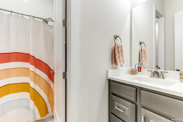 bathroom with a shower with shower curtain, a textured wall, and vanity