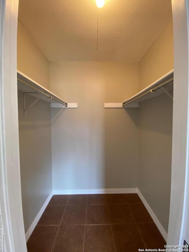 walk in closet featuring dark tile patterned floors