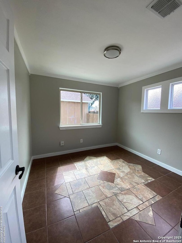 empty room featuring crown molding, a wealth of natural light, and baseboards