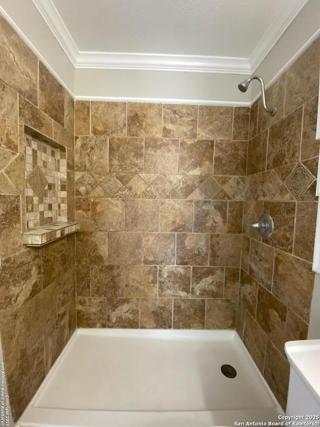 bathroom with ornamental molding and a tile shower