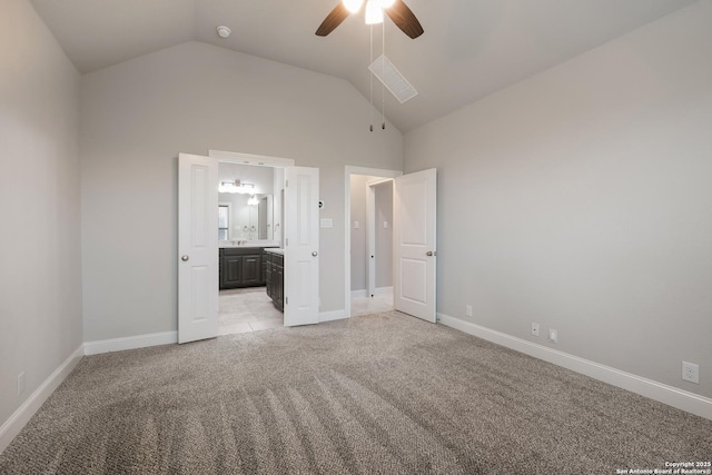 unfurnished bedroom with light carpet, baseboards, lofted ceiling, and connected bathroom