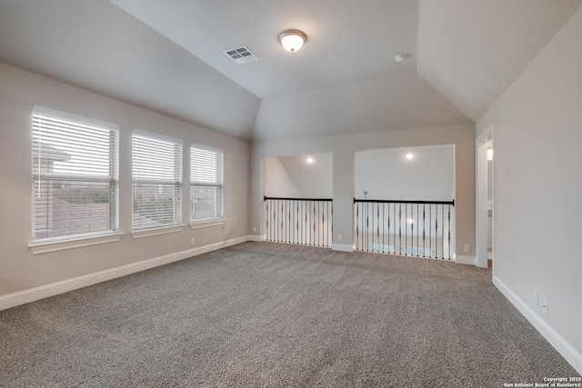 empty room featuring lofted ceiling, baseboards, visible vents, and carpet flooring