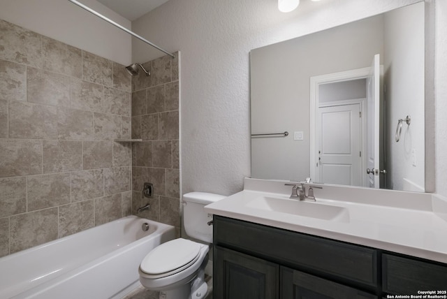 bathroom with a textured wall, bathtub / shower combination, vanity, and toilet