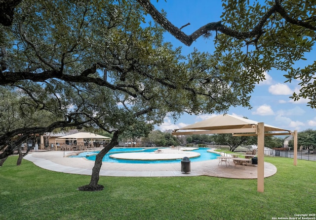 community pool with a patio area, fence, and a lawn