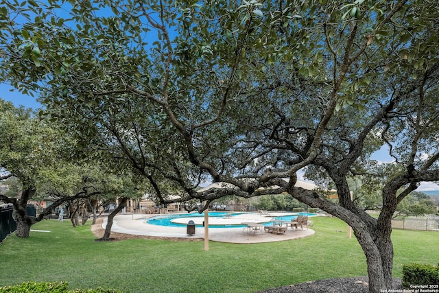 view of property's community featuring a patio area, a swimming pool, fence, and a lawn