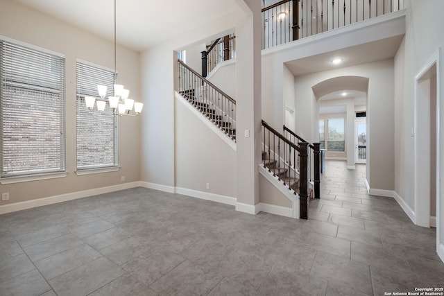 entryway with arched walkways, a high ceiling, stairway, and baseboards