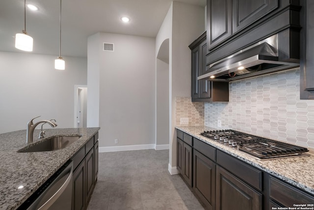 kitchen featuring stainless steel appliances, a sink, visible vents, backsplash, and range hood