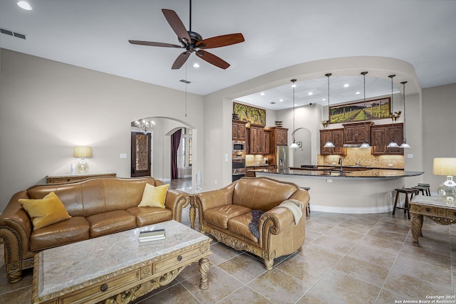 living area featuring arched walkways, a ceiling fan, visible vents, and recessed lighting