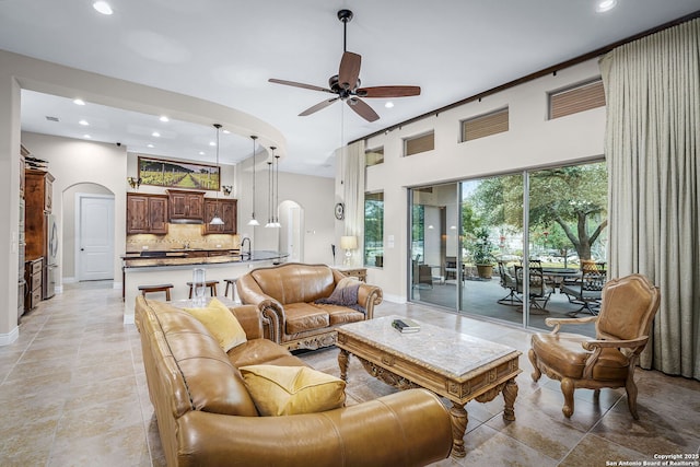 living room featuring arched walkways, a ceiling fan, and recessed lighting